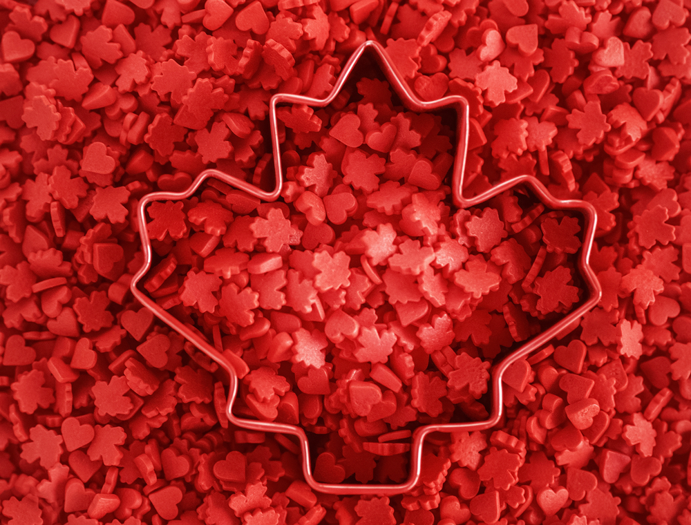 Maple leaf cookie cutter on top of red and heart shaped candies